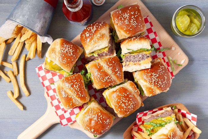 overhead shot of burger sliders with sauce on wooden plank