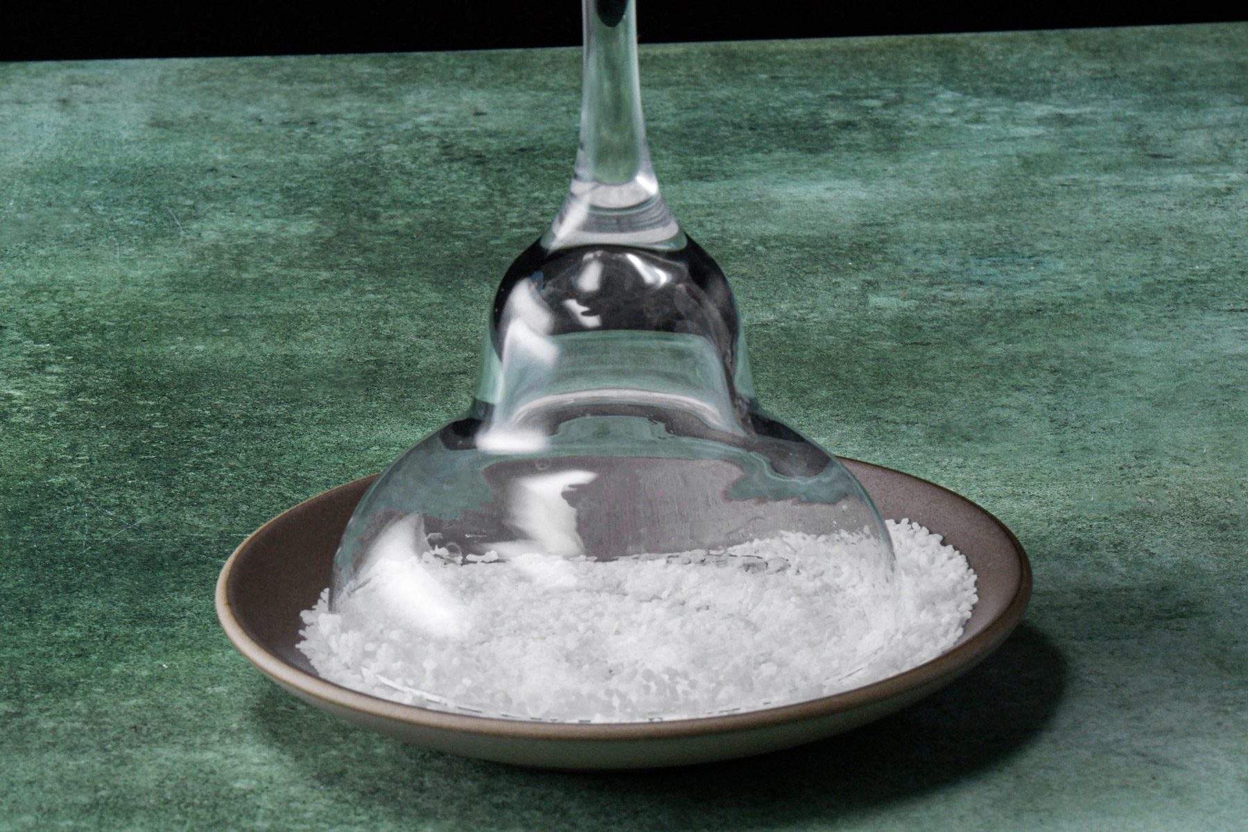 An overturned glass on a plate with salt scattered around it