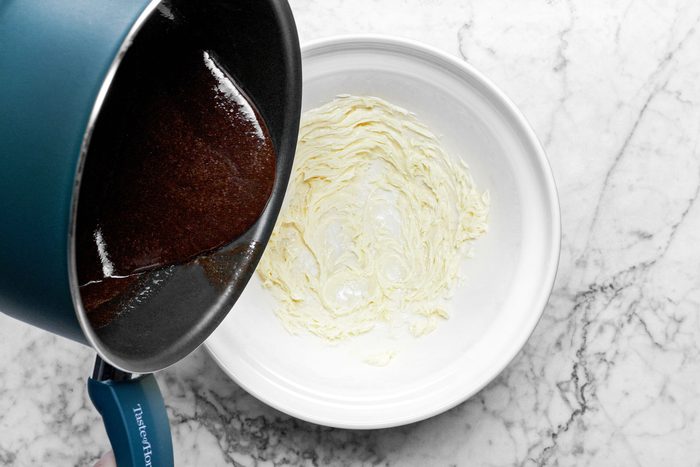 pouring melted chocolate into a large white bowl , marble background