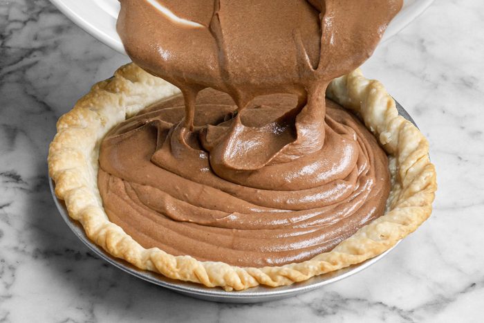 pouring chocolate mixture into a pie crust, marble background