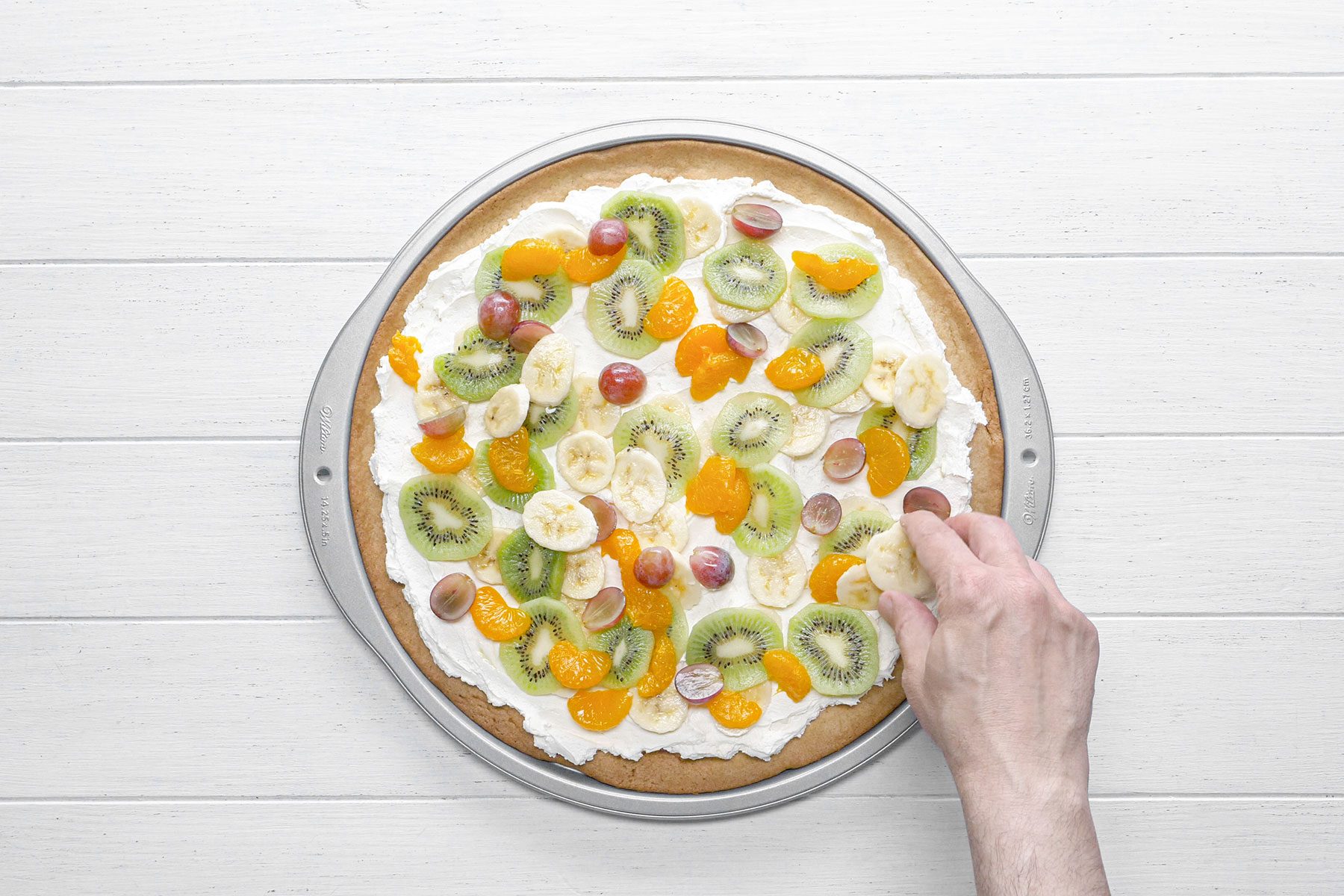 Arranging fruits on pizza base 