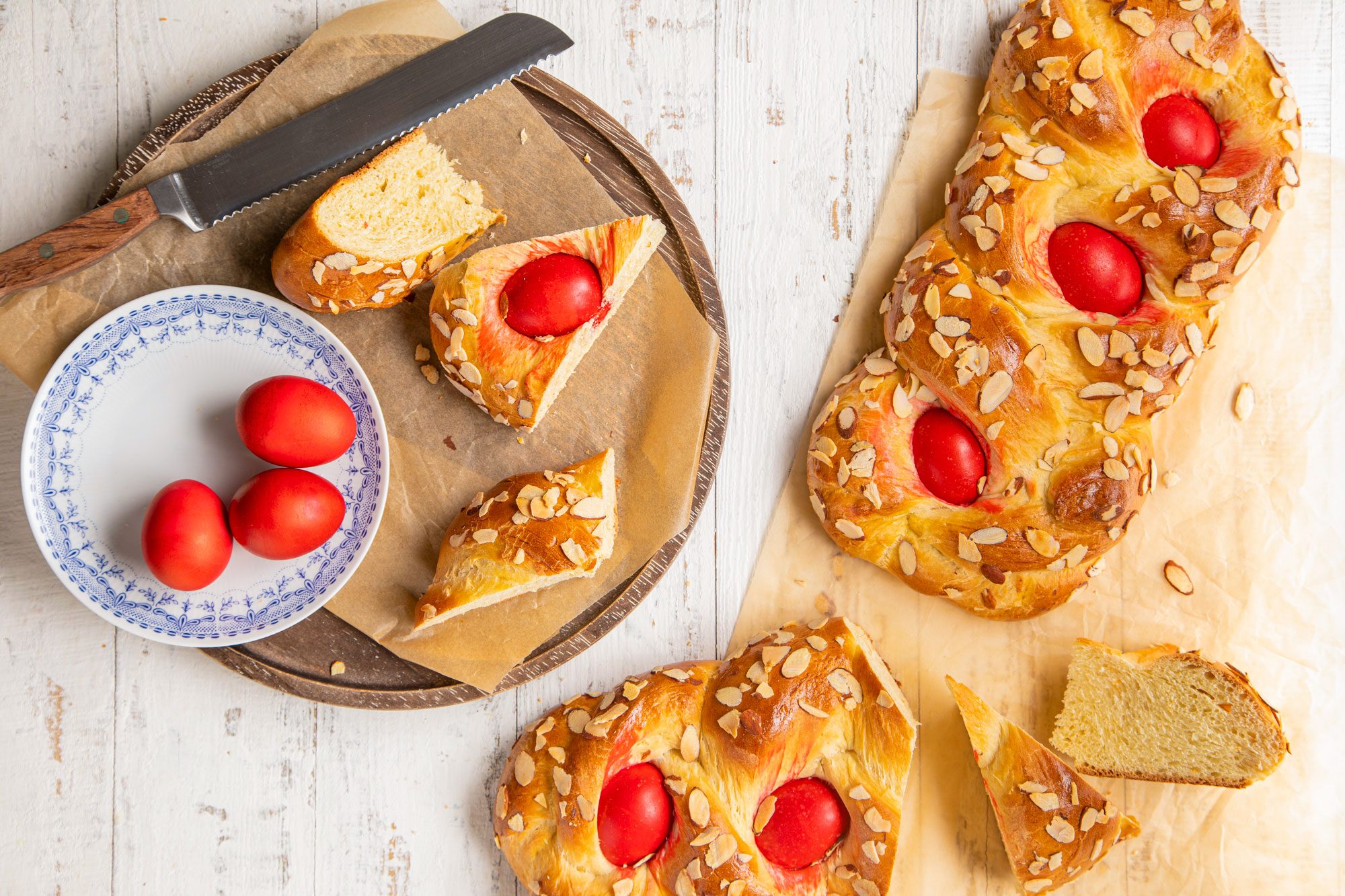 Greek Easter Bread on a Round Wooden Tray with Knife on White Painted Wooden Surface