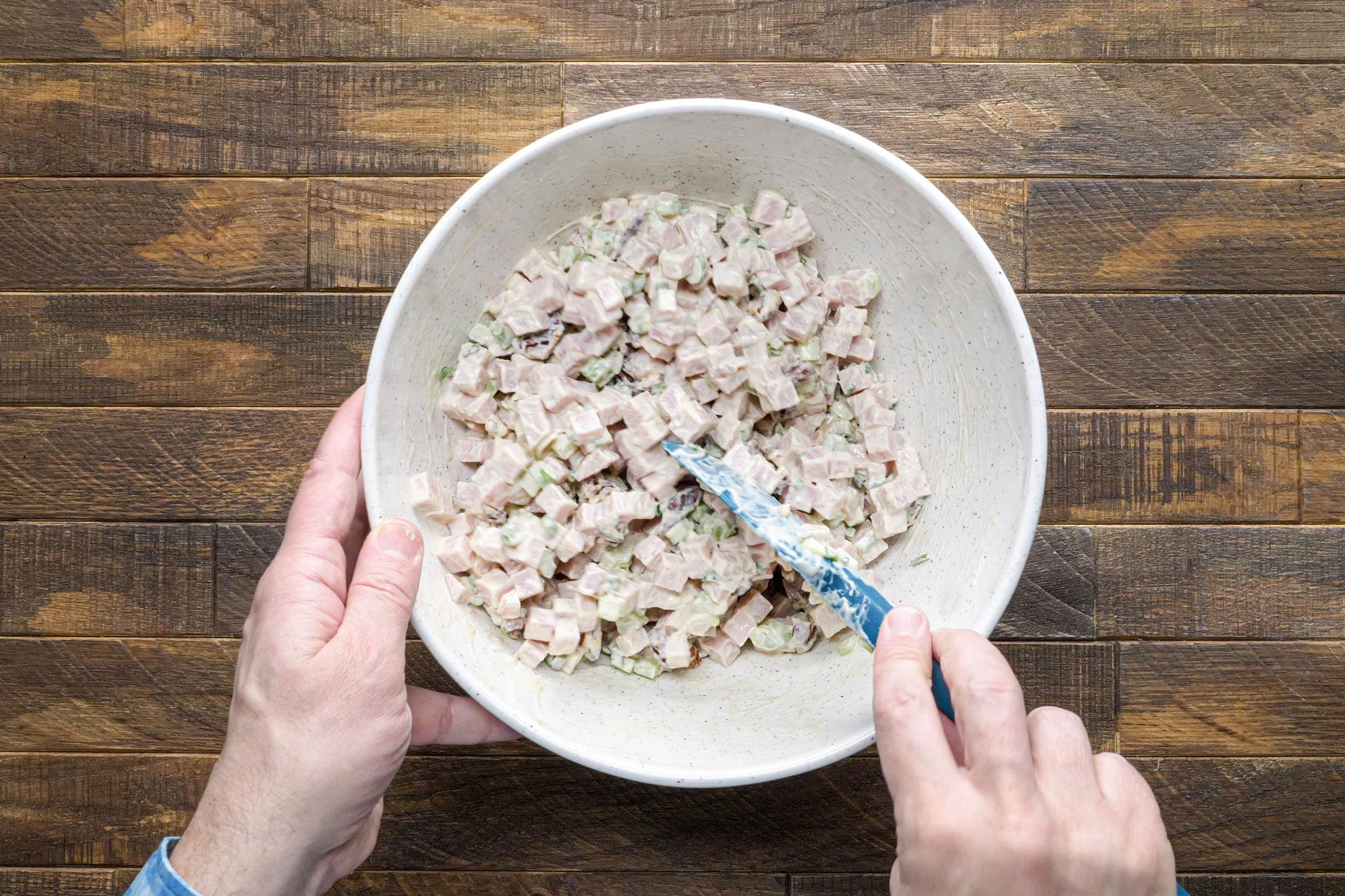 Mixing the diced ham using a spatula in a large bowl.