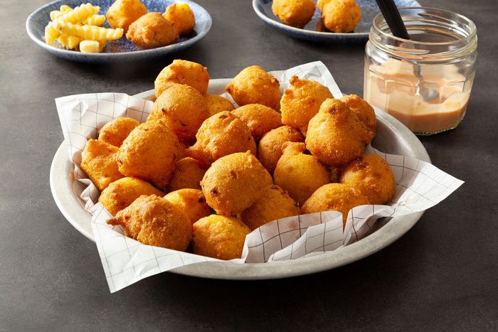 Hush Puppies served in a plate with sauce on a grey marble countertop.