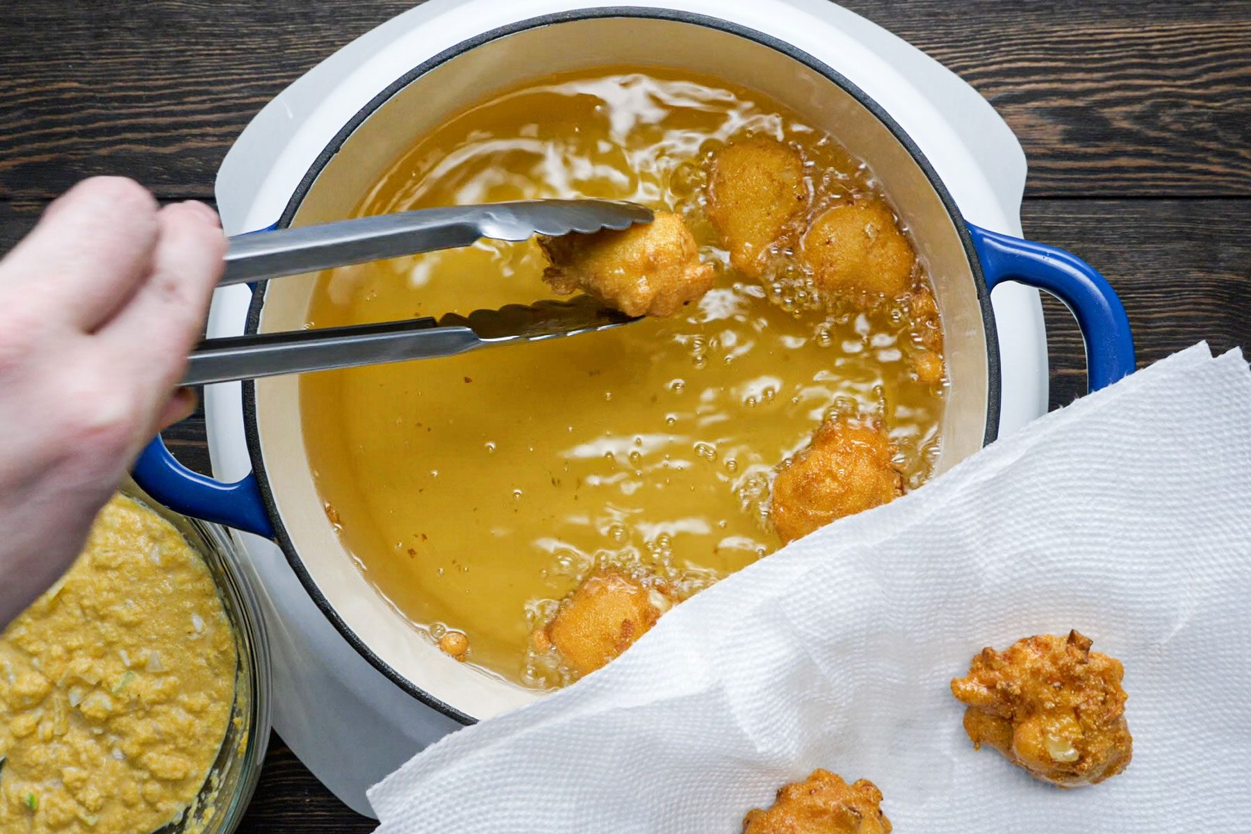 Frying the batter in a large pan on a wooden table.