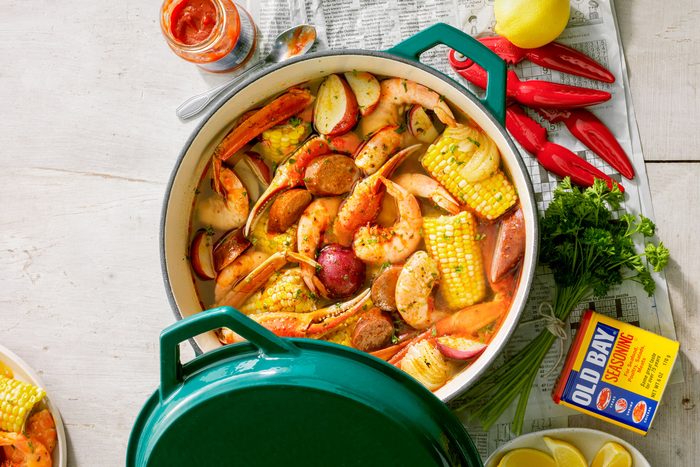 Lowcountry Boil in A Ceramic Cooking Pot on Wooden Surface with Lemon Wedges
