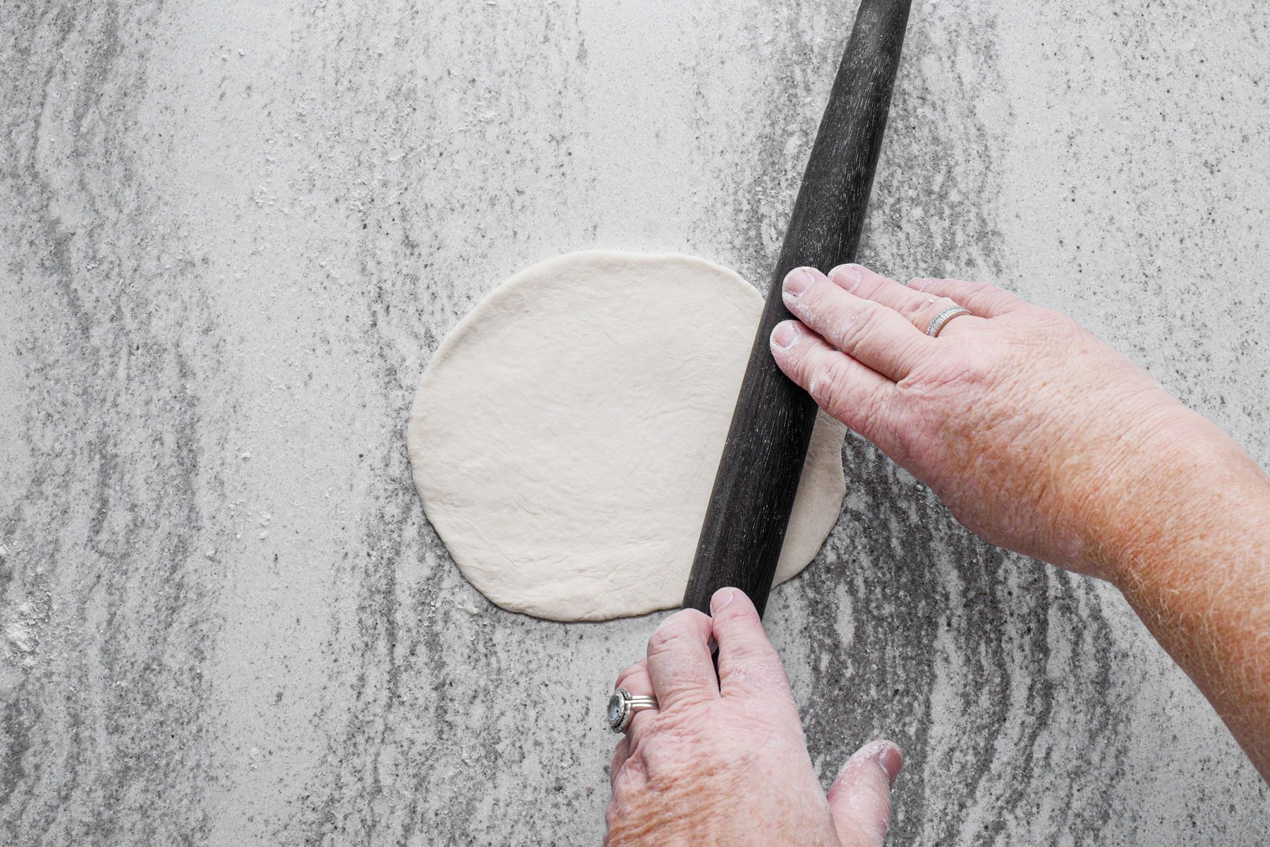 Rolling the dough into small circle shape on a countertop