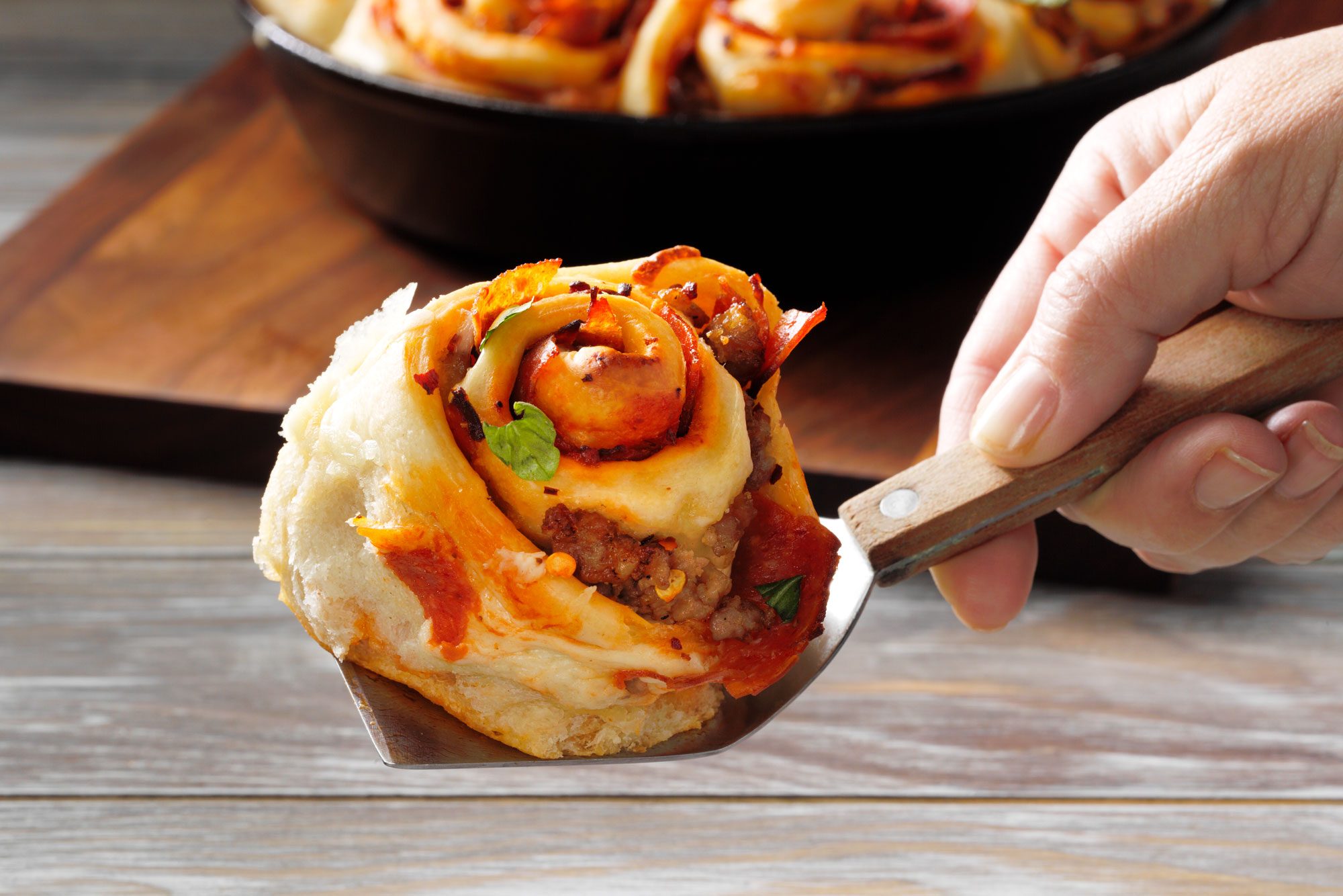Holding a Delicious piece of Cheesy Pizza Roll with Spatula