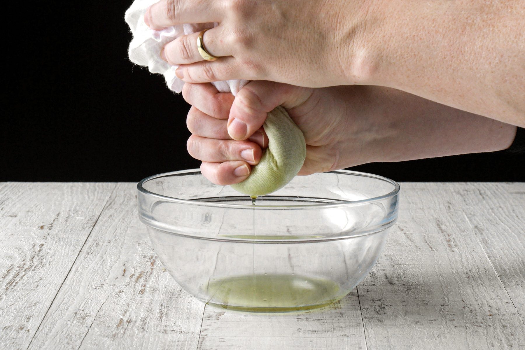 A person squeezing the spinach using a paper towel