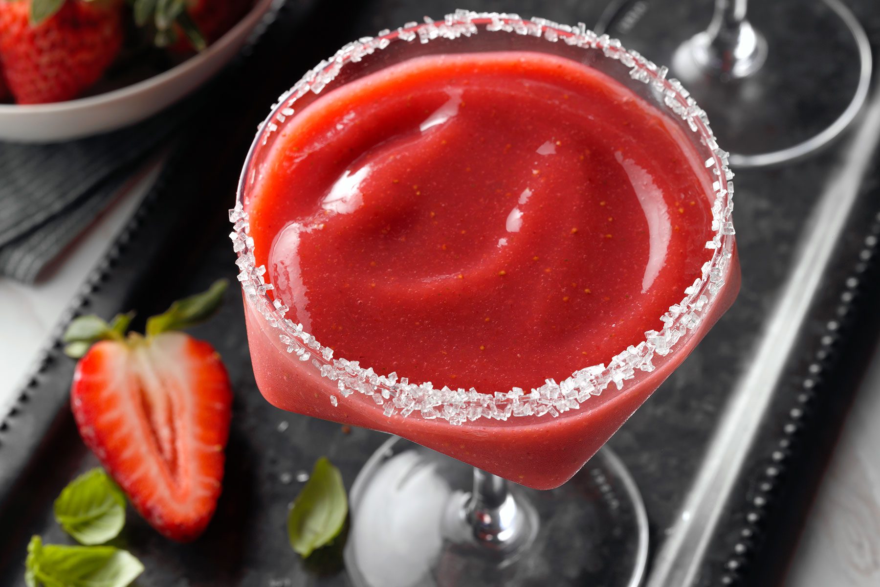 Strawberry Margarita served on black tray with strawberries and mint leaves