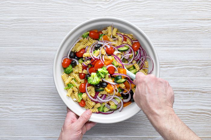 mixing ingredients for pasta salad in a bowl