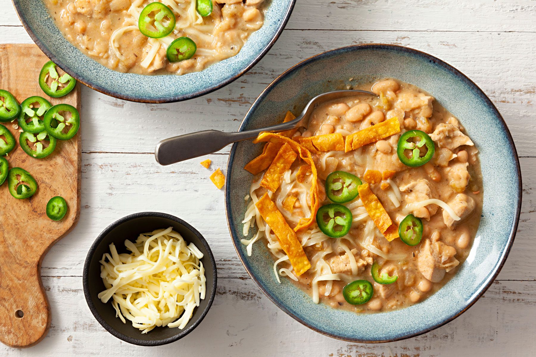 White Chicken Chili alapeno pepper, sour cream and tortilla strips served on a wooden table