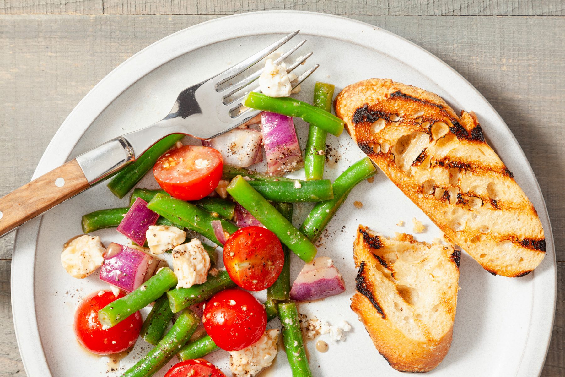 A plate of balsamic green bean salad with fork and knife