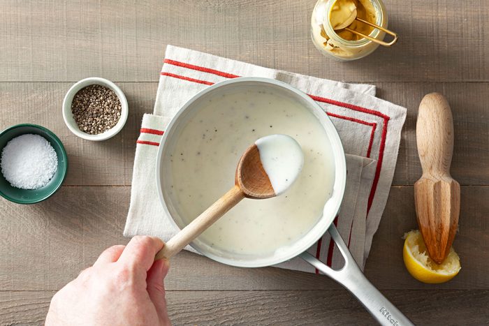 White sauce in a large pan placed on a table cloth on a wooden surface