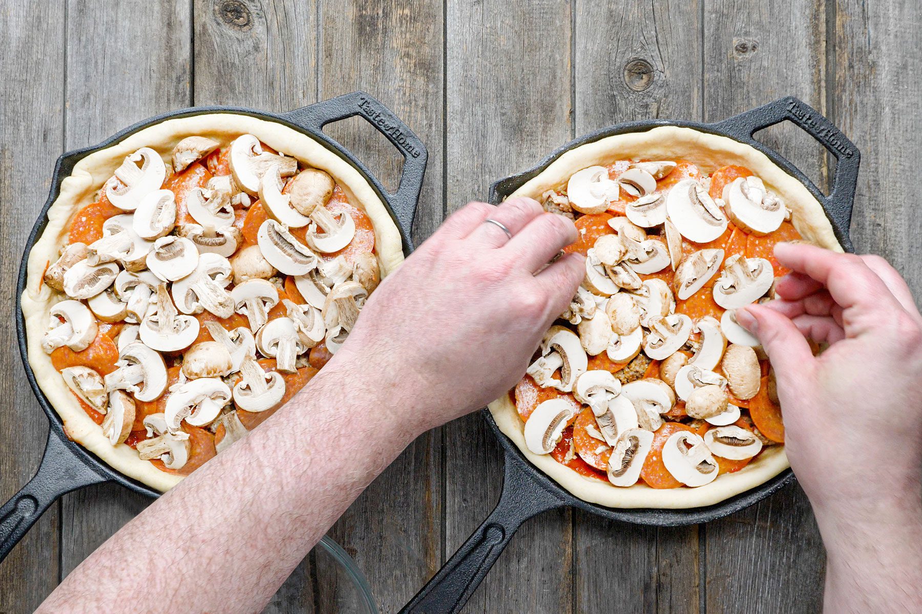 Layering the unbaked pizzas with mushrooms and pepperonis 