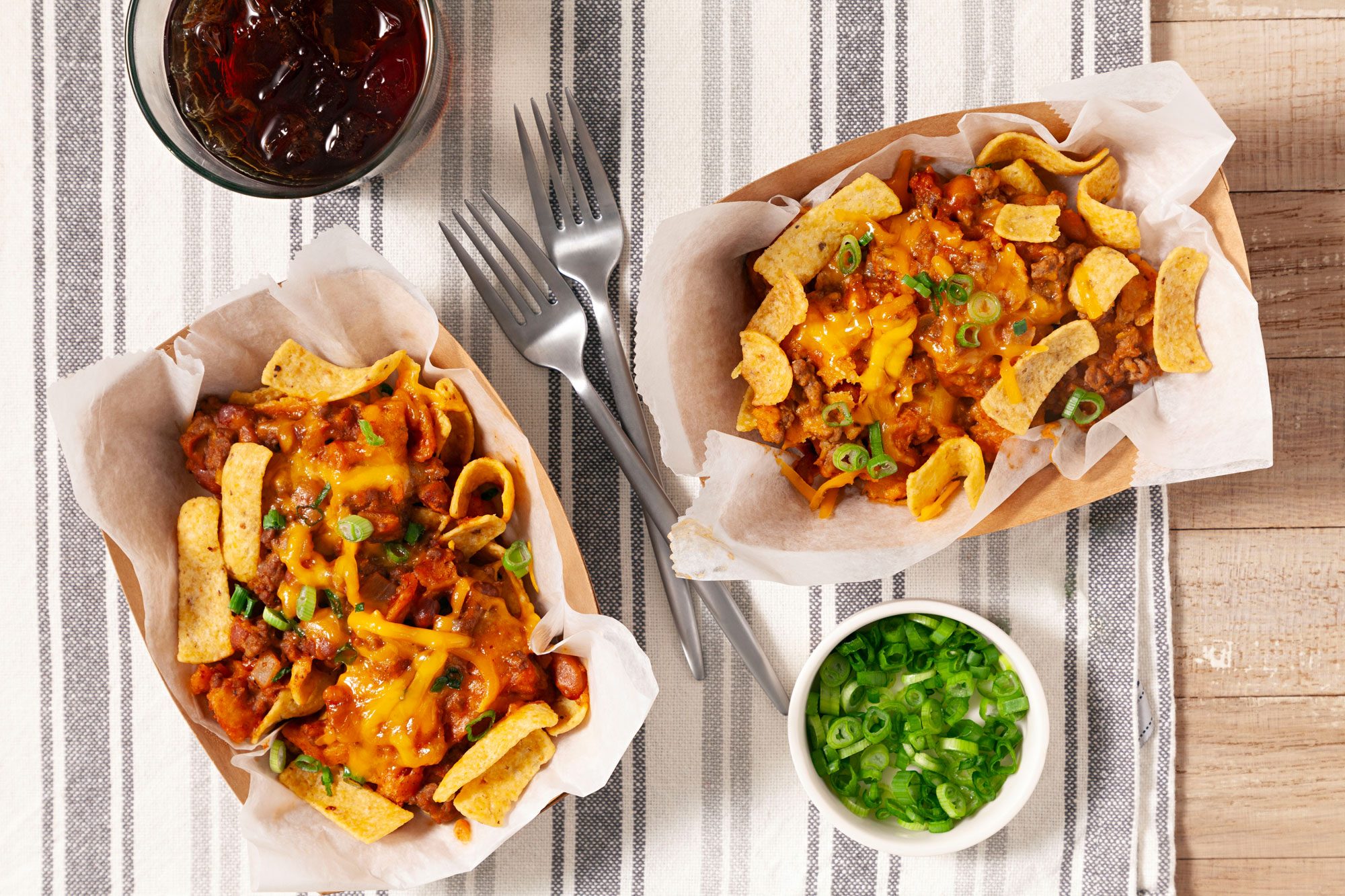 Frito Pie served with diced green onions and coke in serving dish