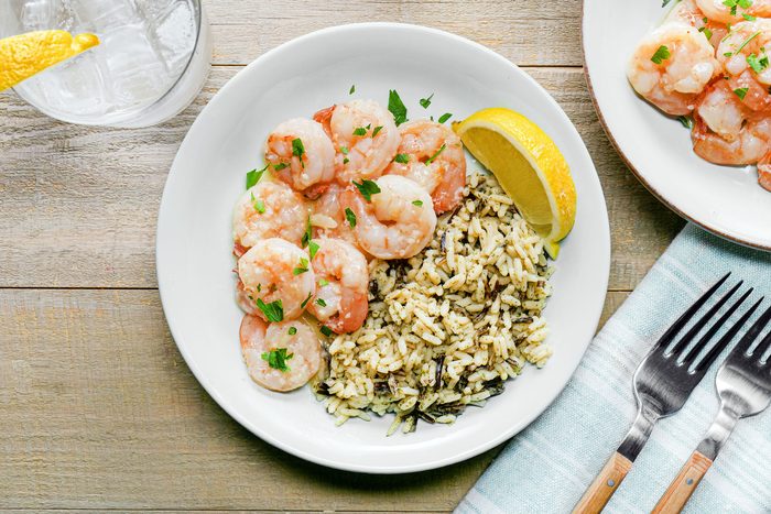 Garlic Butter Shrimp served with rice and lemon in a plate