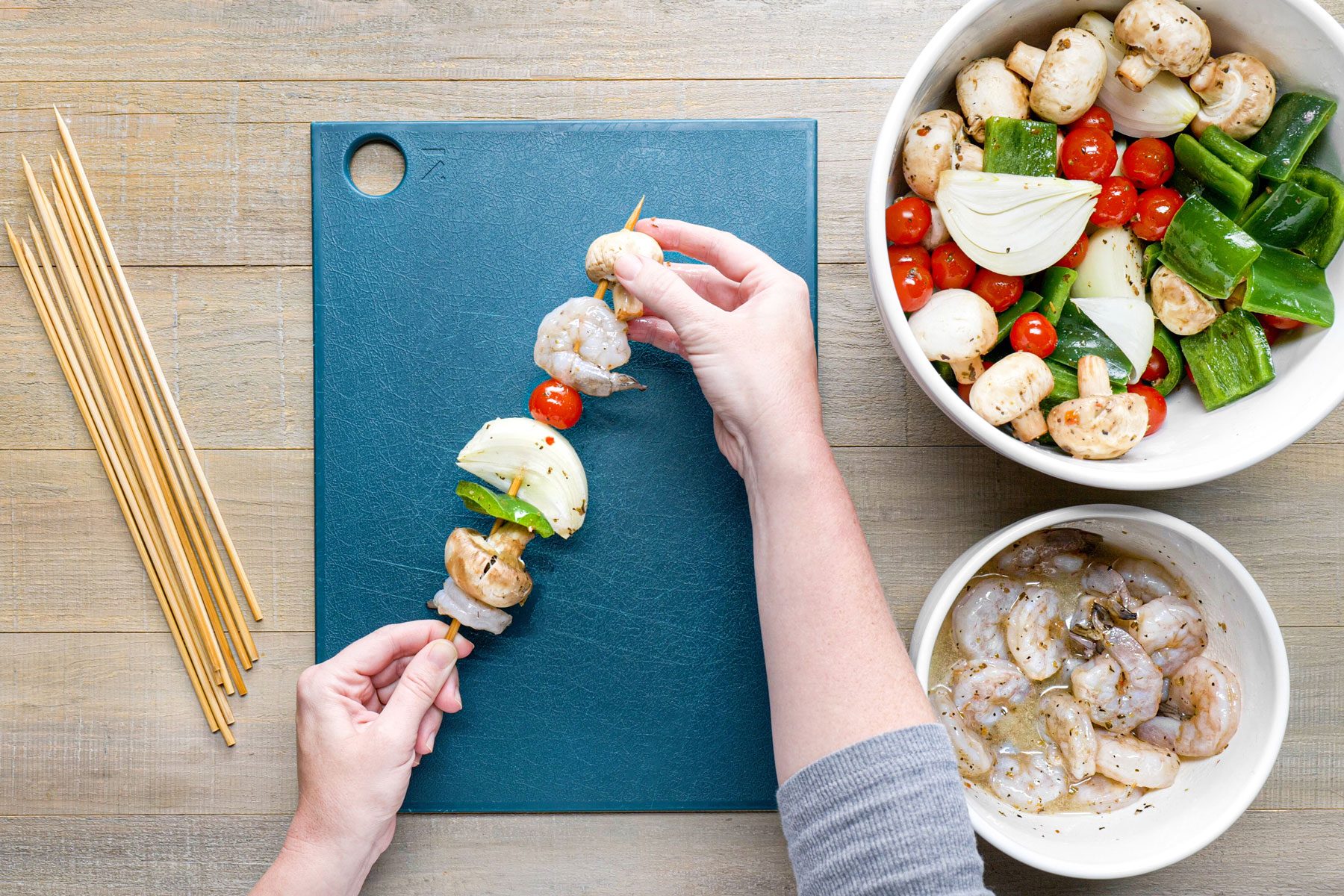 Threading the shrimp and vegetables on wooden skewers 