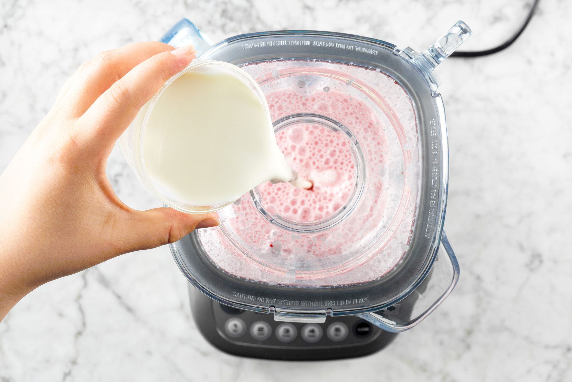 overhead shot of pouring cream into the blender; marble surface;