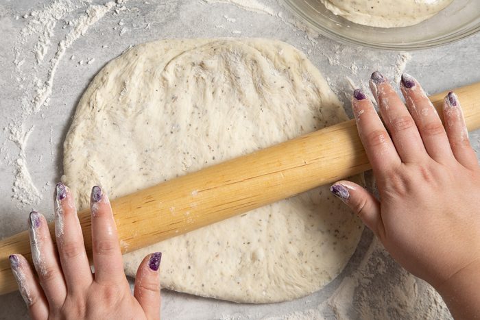 A person rolling out dough with a rolling pin