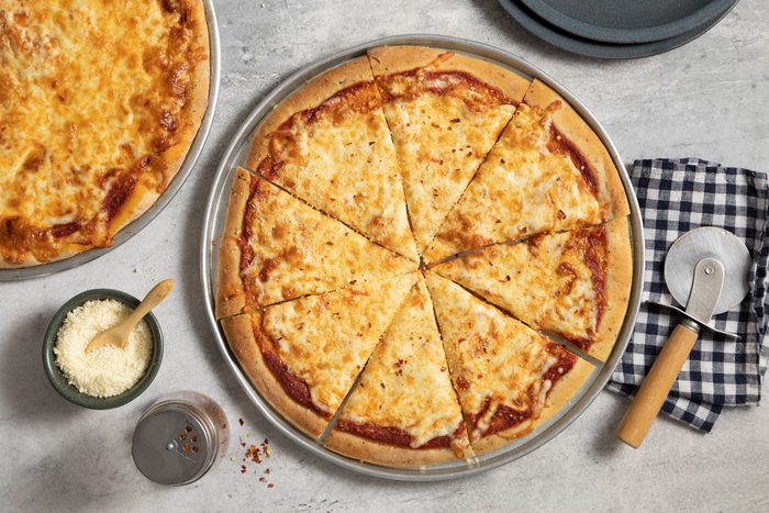 A cheese pizza pan with Parmesan cheese & crushed red pepper flakes