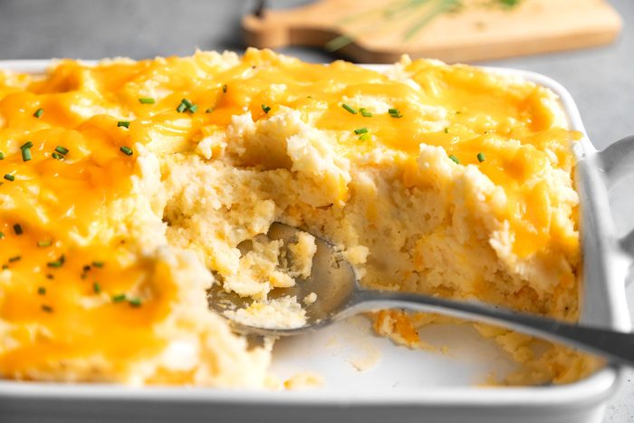 Close up shot of Cheesy Mashed Potatoes in a baking pan with spoon