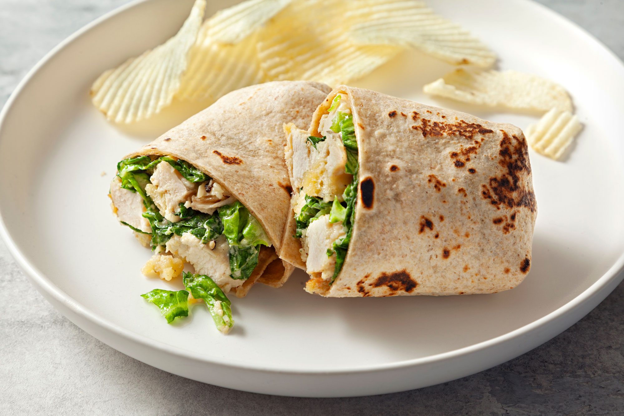 close shot of chicken caesar wraps served with chips