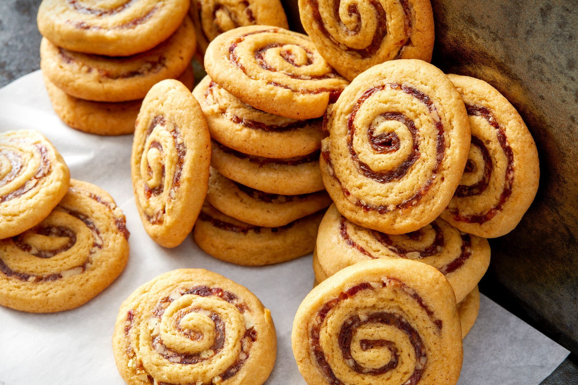 3/4th View Shot of Date Pinwheel Cookies; baking paper; dark background;