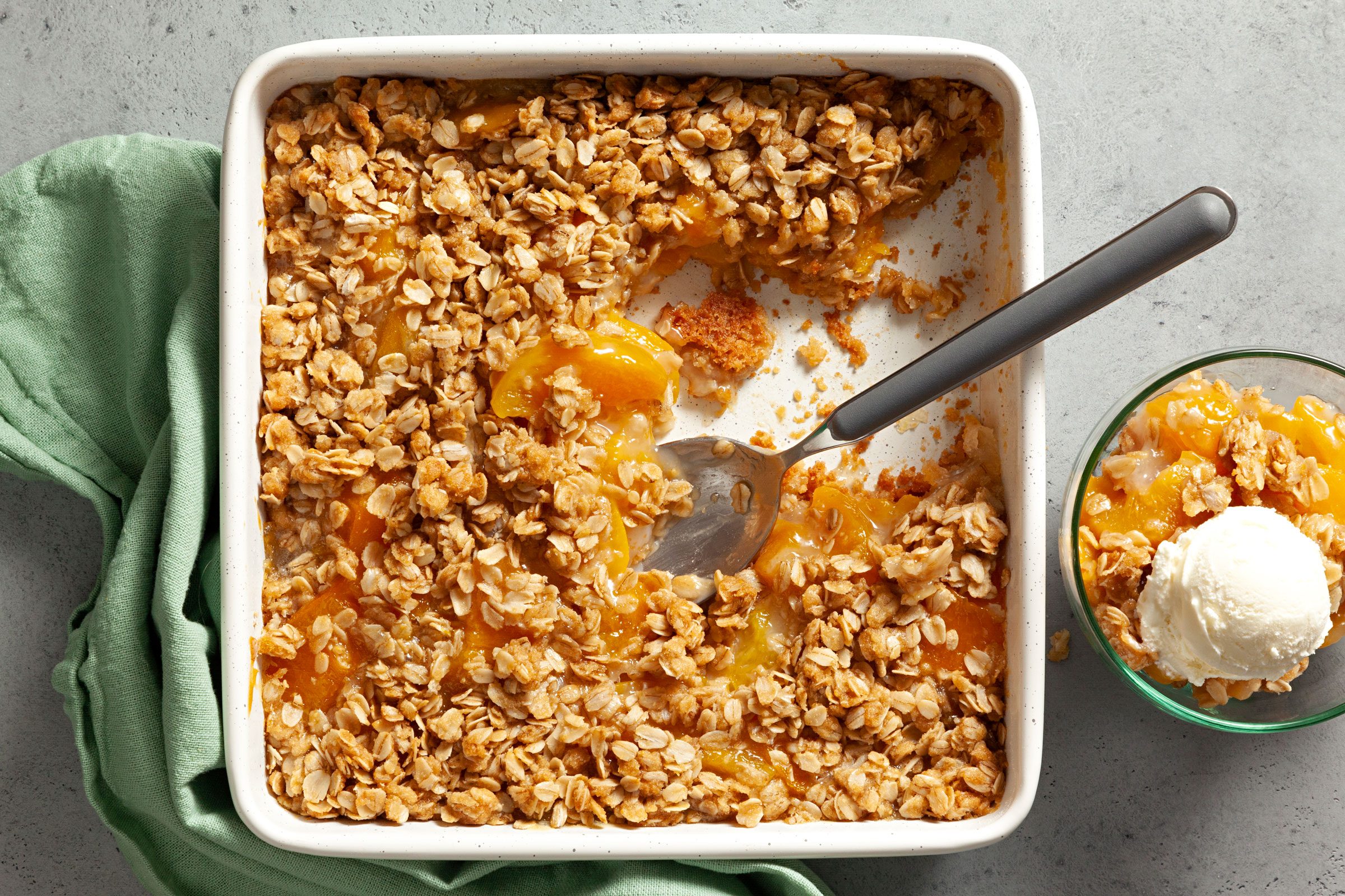 Peach Crisp With Canned Peaches in a baking dish with a section already scooped out