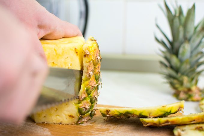 Male hands peeling fresh pineapple skin