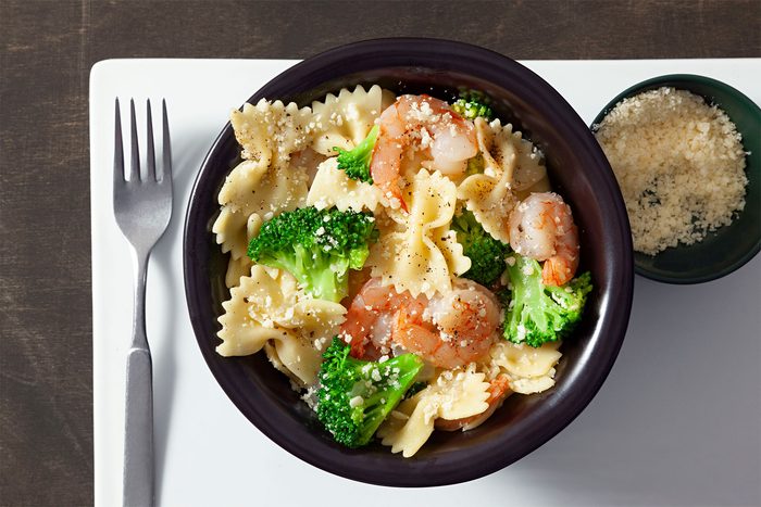 overhead shot of broccoli shrimp pasta toss; parmesan cheese