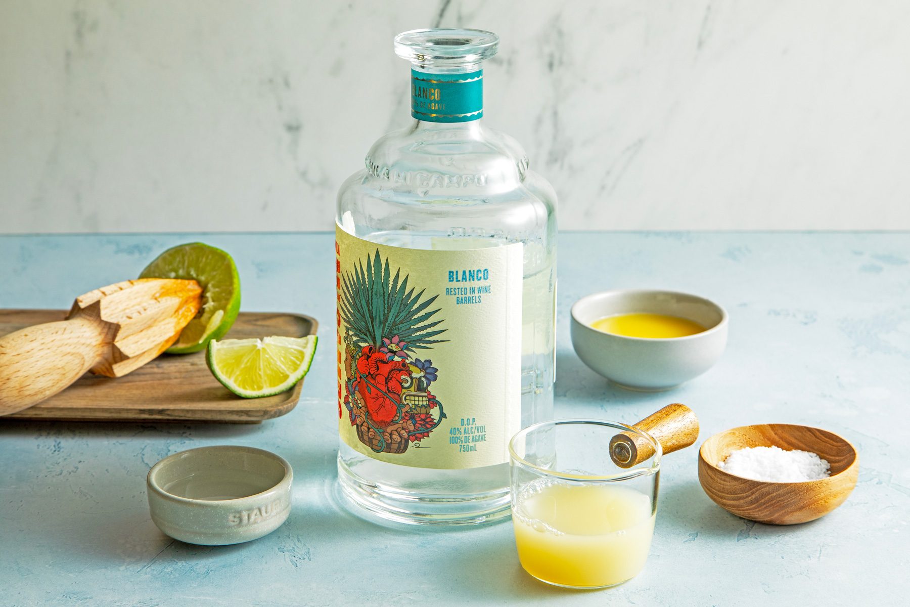 A bottle of tequila with lime slices and orange juice