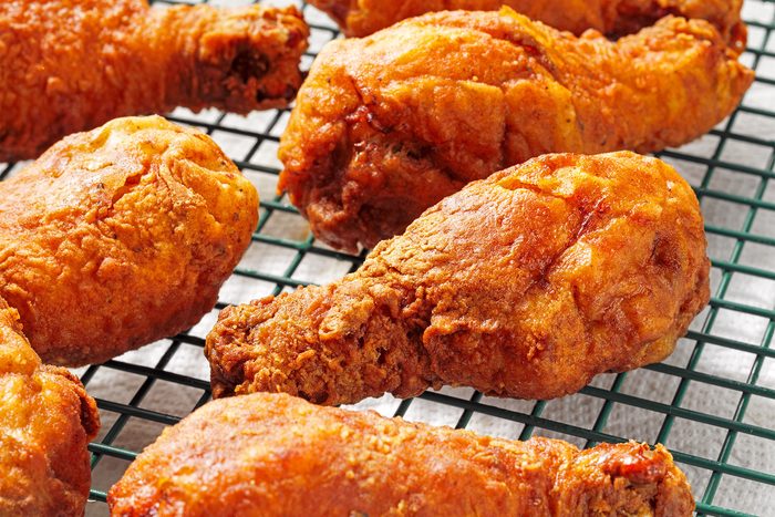 Close shot of Deep-Fried Chicken Legs; placed on wire rack; wooden background;