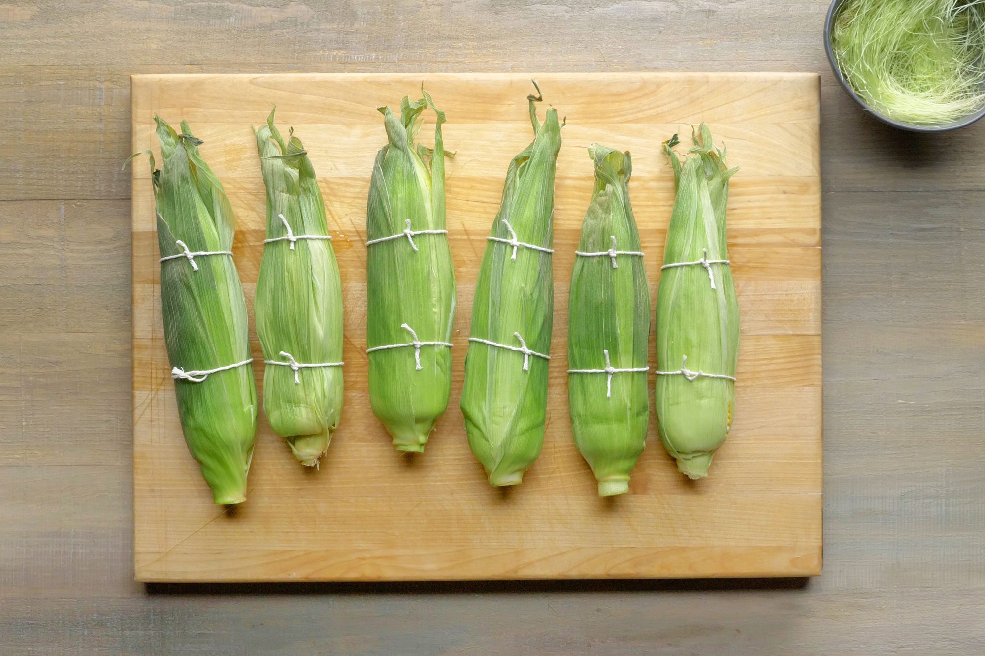 Rewrap each ear of corn in its husk and secure with butcher’s twine