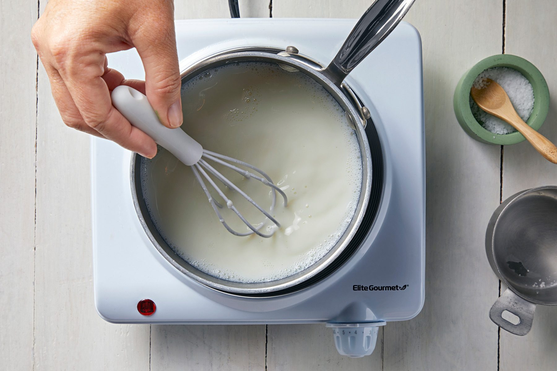 overhead shot; white background; stiring the milk with whisker;