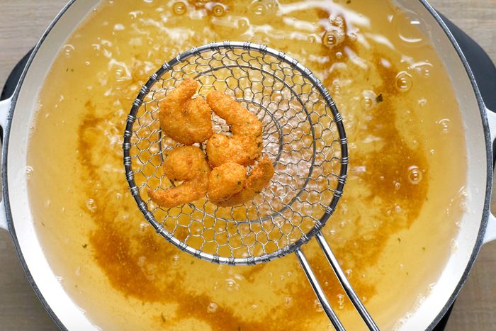 Overhead shot of fry shrimp in batches until golden brown; large skillet; wooden background;