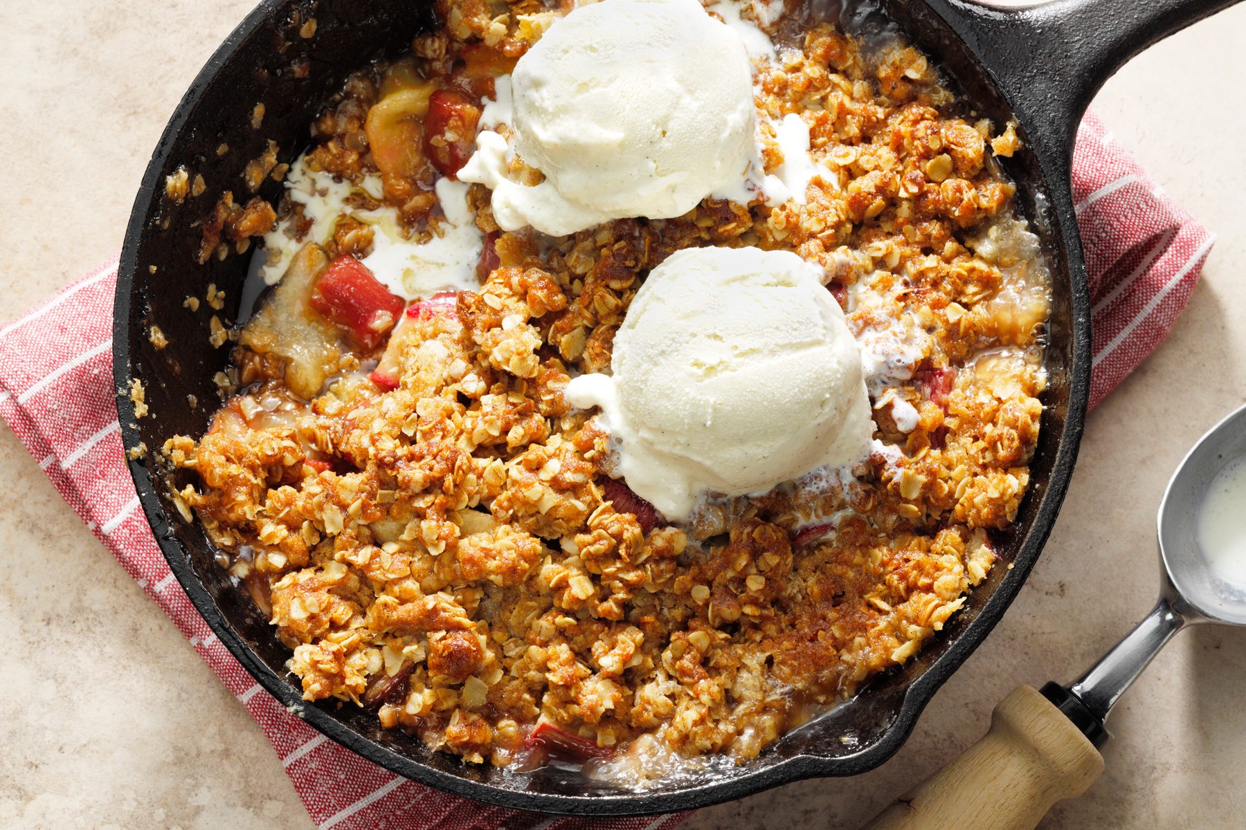 A pan of rhubarb crisp with scoops of vanilla ice cream