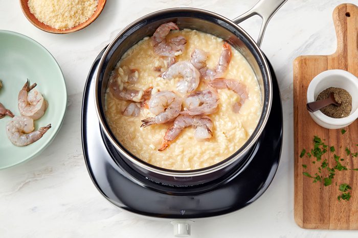 high angle shot of shrimps added in the rice mix in a saucepan