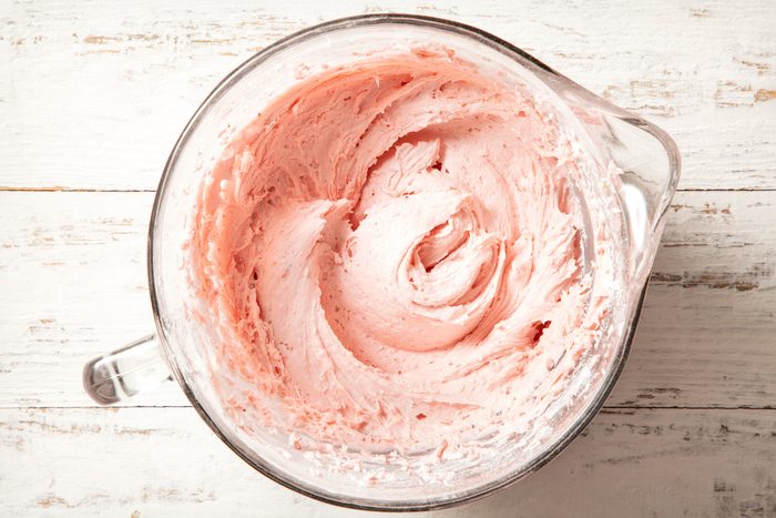 overhead shot of frosted strawberry mixture in a large beaker on white wooden background