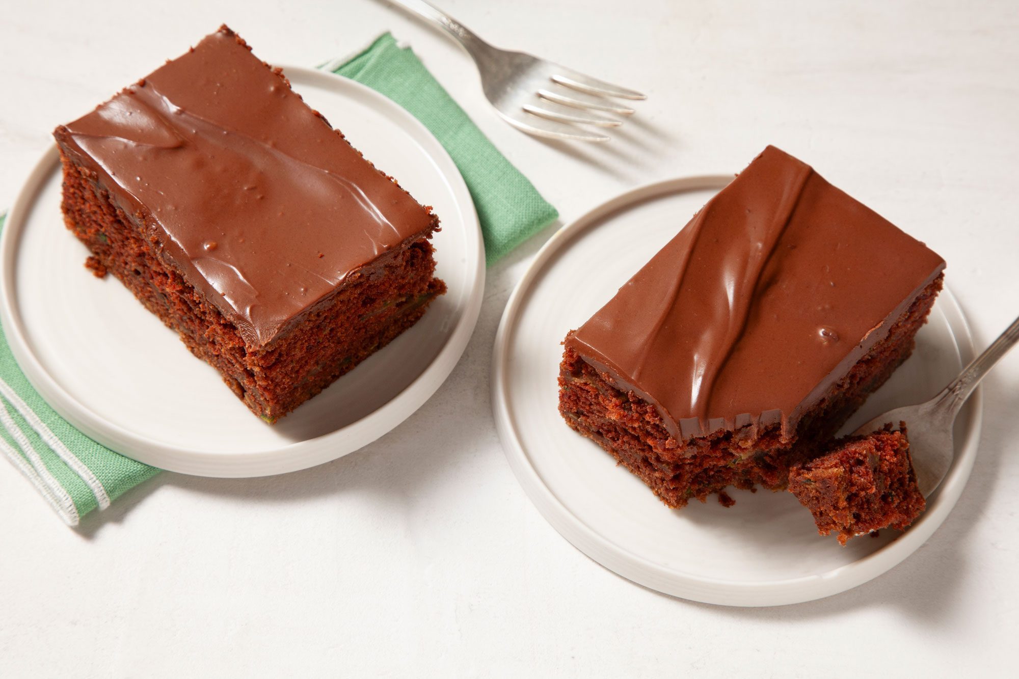 Overhead view shot of Zucchini Brownies; served on two small plates; napkin; forks; marble background;