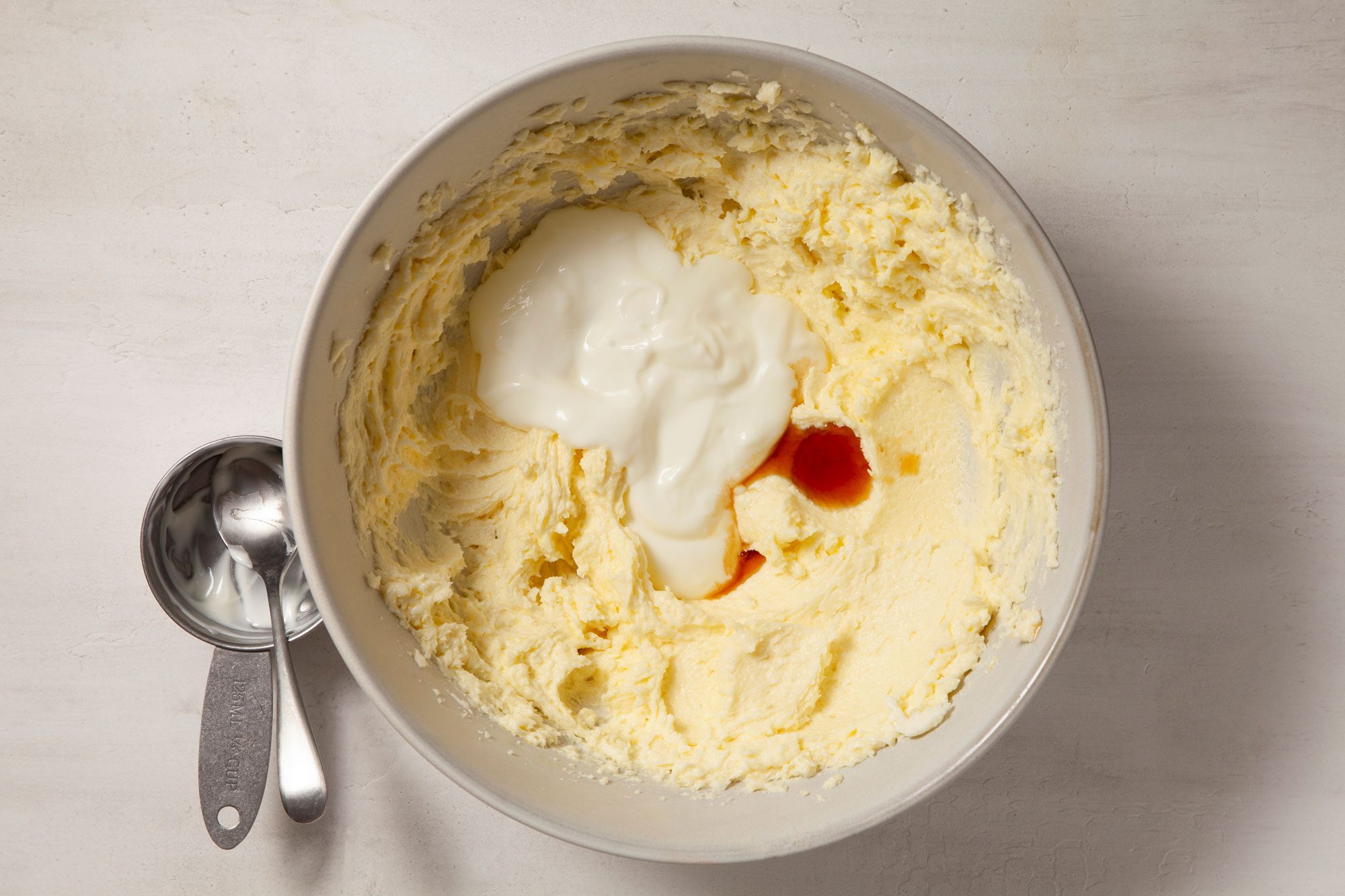 Overhead shot of bowl; beat in yogurt and vanilla; spoons; marble background;