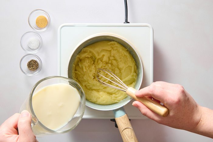 Whisking milk into the roux in a saucepan