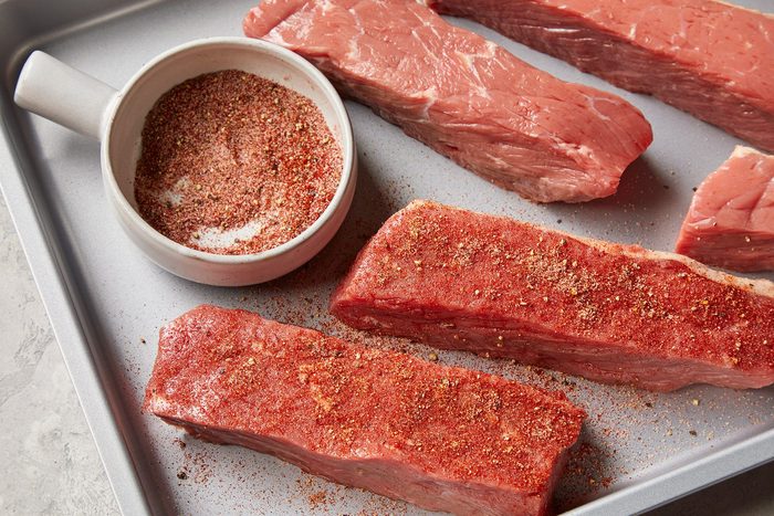 High angle view shot of sprinkle combine mixture over ribs; baking tray; marble background