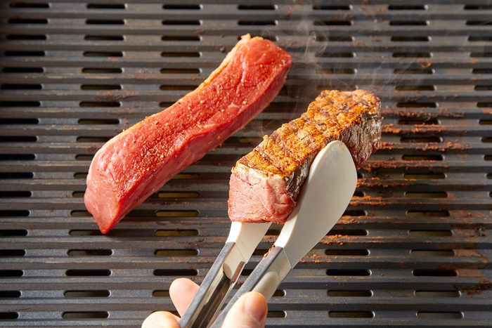 3/4 angle view shot of grill ribs; over medium-high heat; griller; tongs