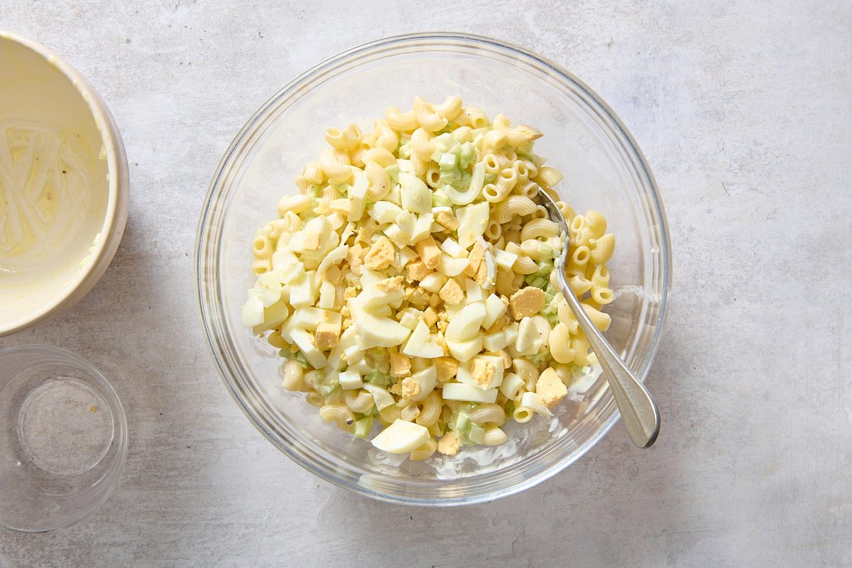 Combining all of the macaroni egg salad ingredients