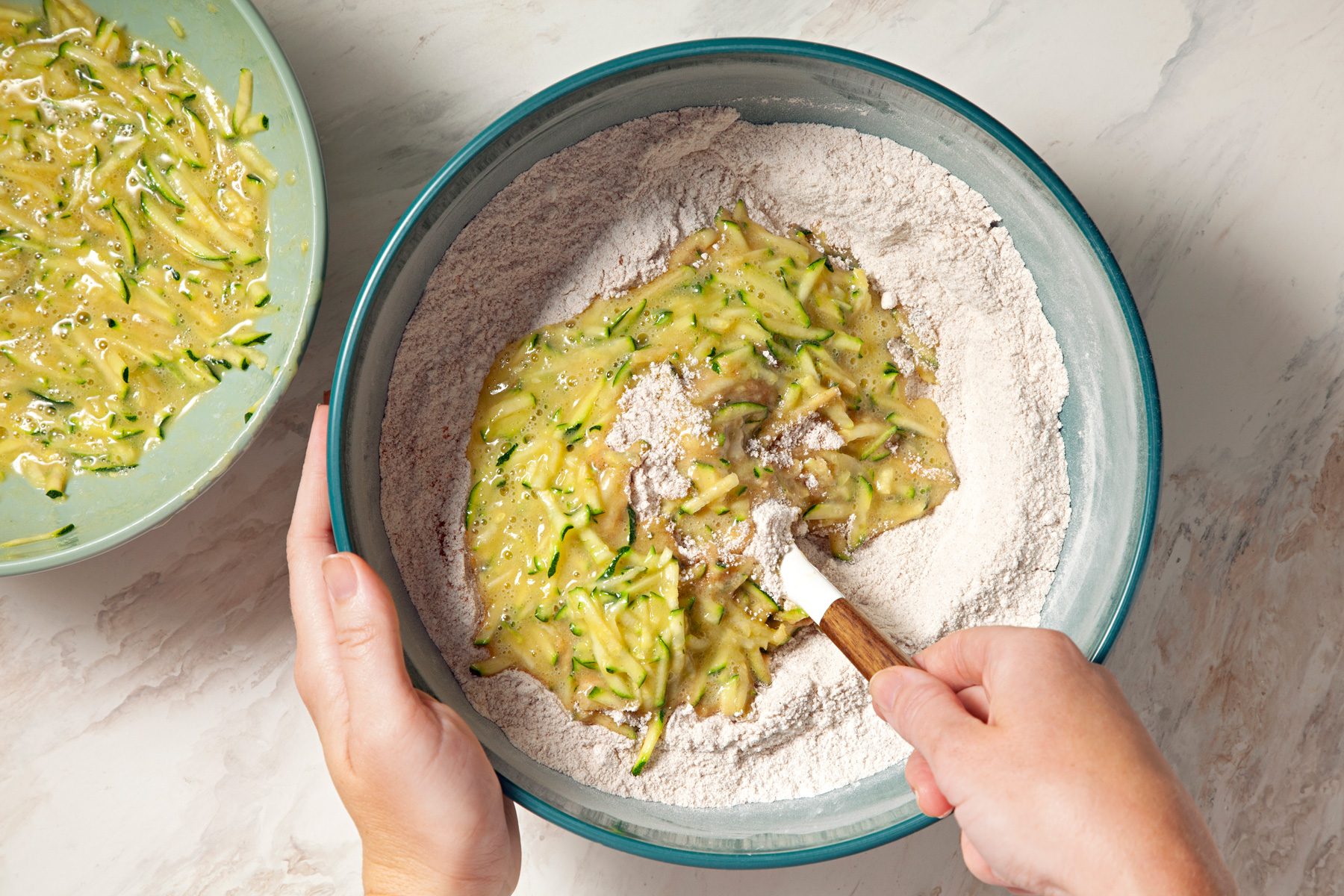 A person stirring zucchini in a bowl