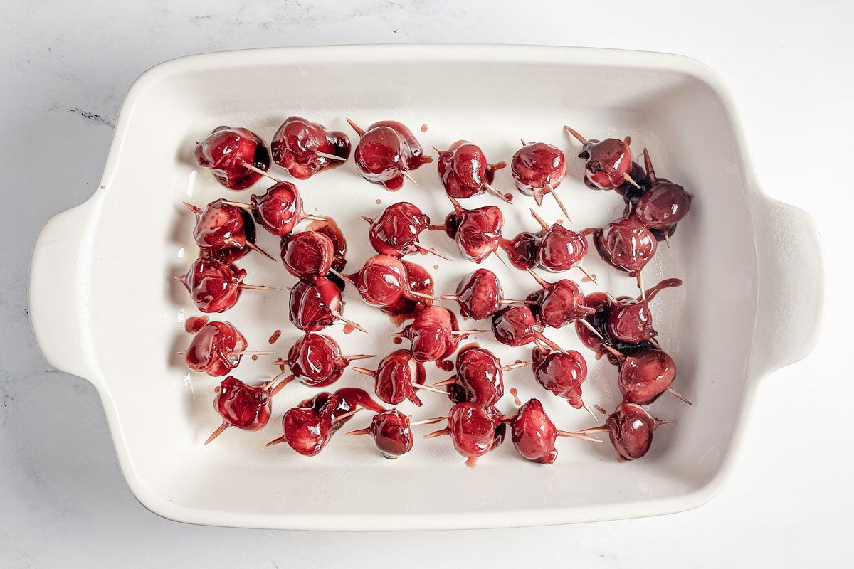 Taste of Home bacon wrapped water chestnuts in a white ceramic baking dish.