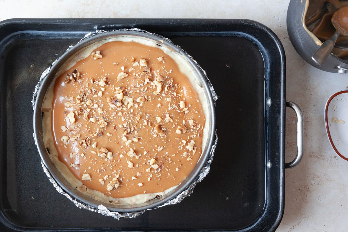 Step 5 of Taste of Home Caramel Apple Cheesecake is to remove from the oven and add the remaining caramel sauce and pecans before returning to oven to finish baking