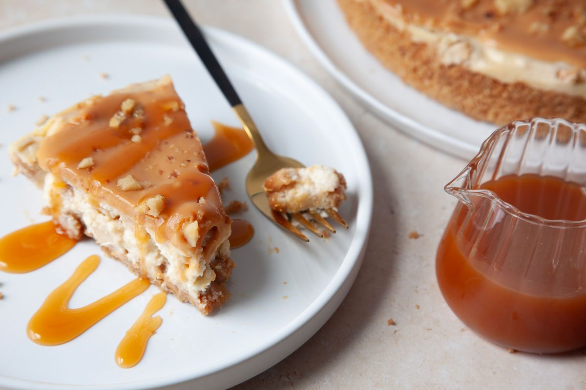 Single serving of Taste of Home Caramel Apple Cheesecake with a small pitcher of caramel sauce