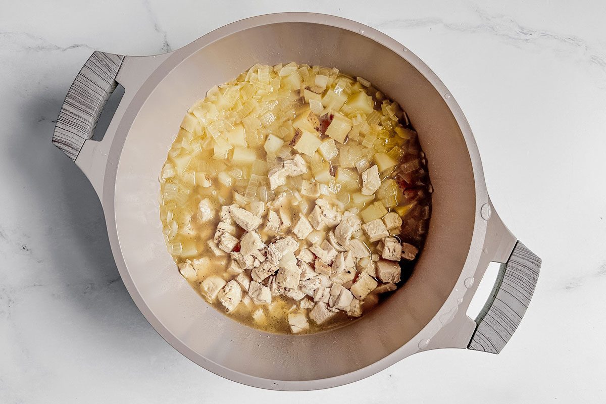 Taste of Home chicken potato soup in a Dutch oven on a marble surface.